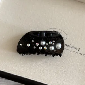 Pinza de pelo semiredonda negra elegantemente decorada con brillante pedrería y perlas.