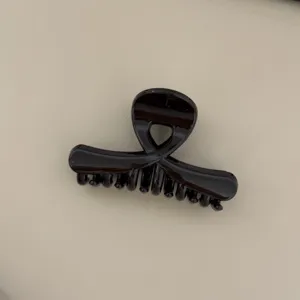 Glossy brown cross hair claw clip, elegant medium size shark clip detail for daily hair styling.