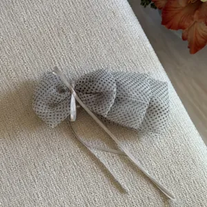 Grey polka dot organza bow hair clip, delicate ribbon detail, stylish hair accessory.