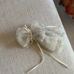 Detail view of sweet floral organza bow hair clip featuring elegant long ribbons.