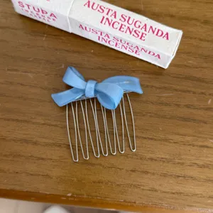 Close up of blue acetate bow hair comb with metal teeth, elegant hair accessory detail view.