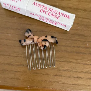 Close-up detail of a fashionable tortoiseshell bow hair comb featuring durable metallic teeth.
