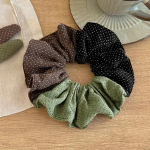 Scunchie per capelli in tessuto a pois vista di dettaglio, morbido accessorio.