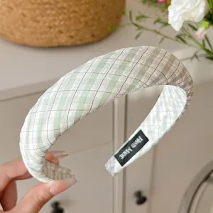 Vue détaillée d'un serre-tête en tissu à carreaux vert et blanc, design large style doux.