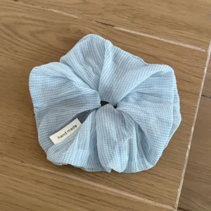 Detail shot of light blue checkered sheer hair scrunchie, soft Korean style hair tie accessory.
