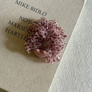 Gros plan d'un chouchou en maille léopard rose avec accent cœur mignon et texture douce.