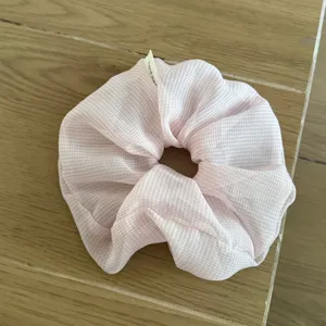 Close-up detail of a pink gingham sheer fabric hair scrunchie showcasing its soft texture.