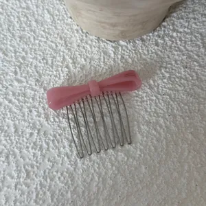 Pink acetate bow hair comb detail view, elegant metal teeth side hair accessory for daily styling.