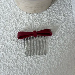 Detail view of the red acetate bow hair comb featuring metal teeth for stylish side hair styling.