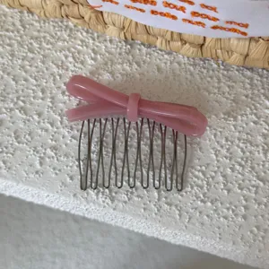 Detalle de peine para pelo con lazo de acetato rosa, bonito accesorio lateral elegante.