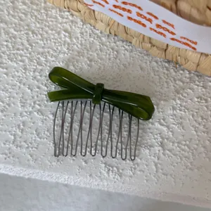 Detalle de peine para el pelo con lazo de acetato verde oscuro, peine de metal elegante.
