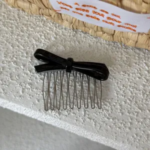 Detalle en primer plano de un elegante peine para el pelo con lazo de acetato negro.