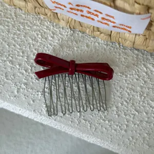 Vista detallada de peine para el pelo con lazo rojo, elegante accesorio de acetato con dientes.
