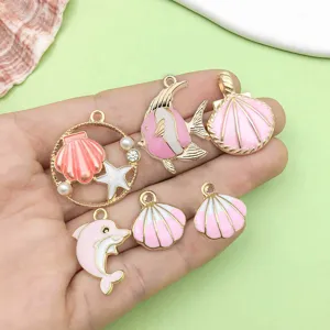 Pink oil drop alloy ocean theme shell and fish pendant charms close up detail shot for DIY jewelry.