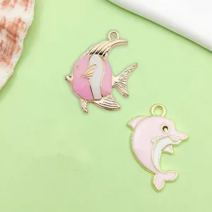 Close up detail of pink enamel alloy ocean dolphin and fish charms for DIY jewelry making accessories.