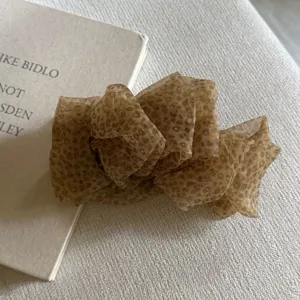 Close-up of a Korean style fluffy leopard print organza bow hair clip detail on texture.