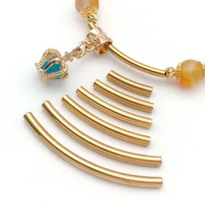 Detail view of stainless steel gold curved tube pendants and DIY jewelry making accessories parts.