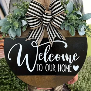 Close-up of wooden welcome door sign with striped bow and green eucalyptus leaves