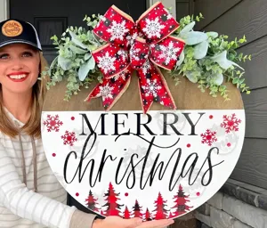 Nahaufnahme eines rustikalen hölzernen Merry Christmas Türschilds mit großer karierter Schleife