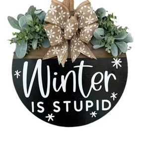 Rustic wooden front door sign featuring Winter Is Stupid text with burlap bow and greenery