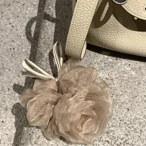 Vue détaillée de l'élastique à cheveux en organza fleur champagne, texture délicate des pétales.