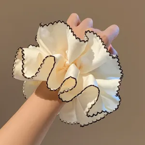 Close-up detail van de stijlvolle beige satijnen haarscrunchie met dubbele laag textuur.