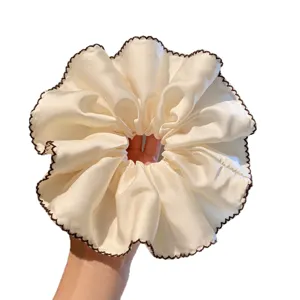 Beige satin haarscrunchie met bruine rand, elegant haaraccessoire voor dagelijks gebruik.