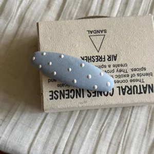 Gros plan détail de la jolie pince à cheveux bleue à pois montrant une texture douce et fine.