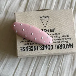 Détail de pince à cheveux BB rose à pois, accessoire mignon pour coiffure de frange quotidienne.