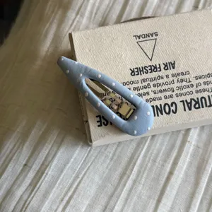 Gros plan d'une jolie pince à cheveux à pois avec revêtement en cuir et base métallique.