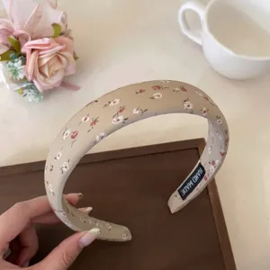Vista detallada de la dulce diadema floral, con pequeñas flores sobre un tejido beige.