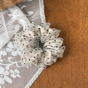 Mesh polka dot hair scrunchie detail view, showing soft sheer fabric and cute black dots.