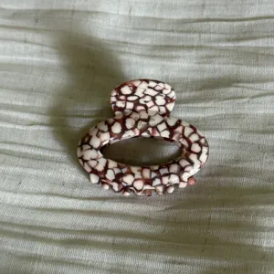 Close-up of elegant oval hair claw clip with unique tortoiseshell mosaic pattern design.