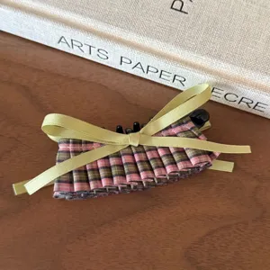 Detalle de pinza para el pelo a cuadros estilo coreano con lazo de satén y tela plisada.