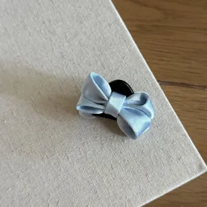 Detail shot of a light blue satin bow hair claw clip showcasing its delicate fabric and texture.