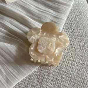 Close-up detailopname van een beige bloemvormige acetaat haarclip met stijlvol ontwerp.