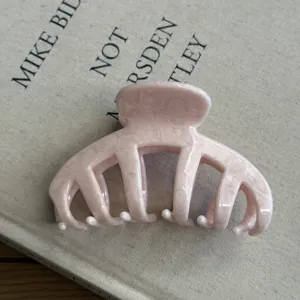 Close up of a retro pink acetate hair claw clip, featuring a large design for thick hair styling.