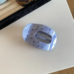 Detail shot of the blue dotted acetate hair claw clip, showing its glossy finish and unique pattern.
