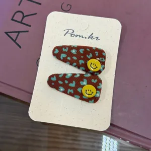 Pinzas para el pelo retro con estampado de leopardo y botones smiley amarillos.