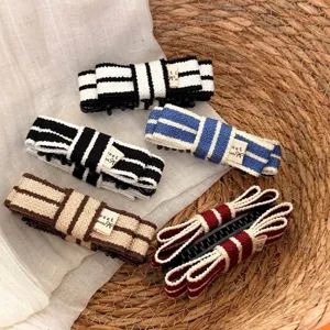 Detailed shot of Korean style color contrast striped knitted bow hair claw, versatile hair accessory.