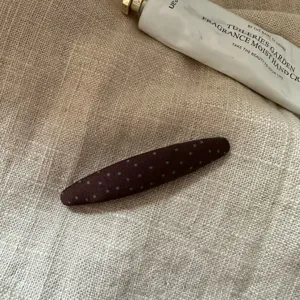 Braune Stoff-Schnapphaarspange im Detail, mit niedlichem Punktmuster für seitliches Haarstyling.