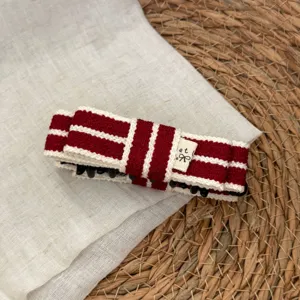Close-up detail of red and white striped knit hair claw clip with a cute fabric label tag.
