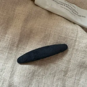 Nahaufnahme der dunklen, geflockten ovalen Haarklammer mit weicher Textur und schlichtem Design.