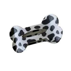 Bone shaped hair claw clip with black and white cow spot pattern for women daily hair styling use.