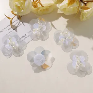 Transparent sequin flower applique with pearl center, detailed view of handmade craft material.