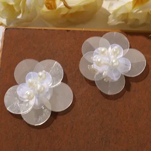Close-up of handmade double-layer clear sequin flower with faux pearl center for DIY crafts.