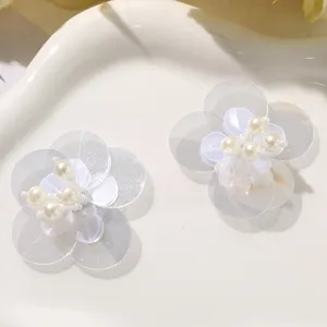 Close-up of white sequin flower appliques with faux pearl centers for DIY crafts.