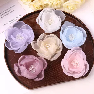 Close-up detail of sweet mesh flower hair clips with pearl centers arranged on wooden tray.