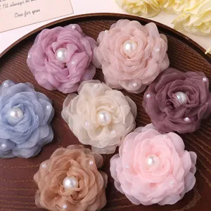 Detailed close-up of handmade organza camellia flowers with faux pearls for DIY hair accessories.
