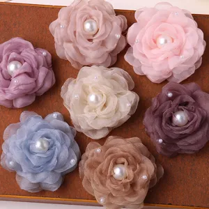 Close up of colorful mesh fabric camellia flowers with pearl center, DIY accessory.